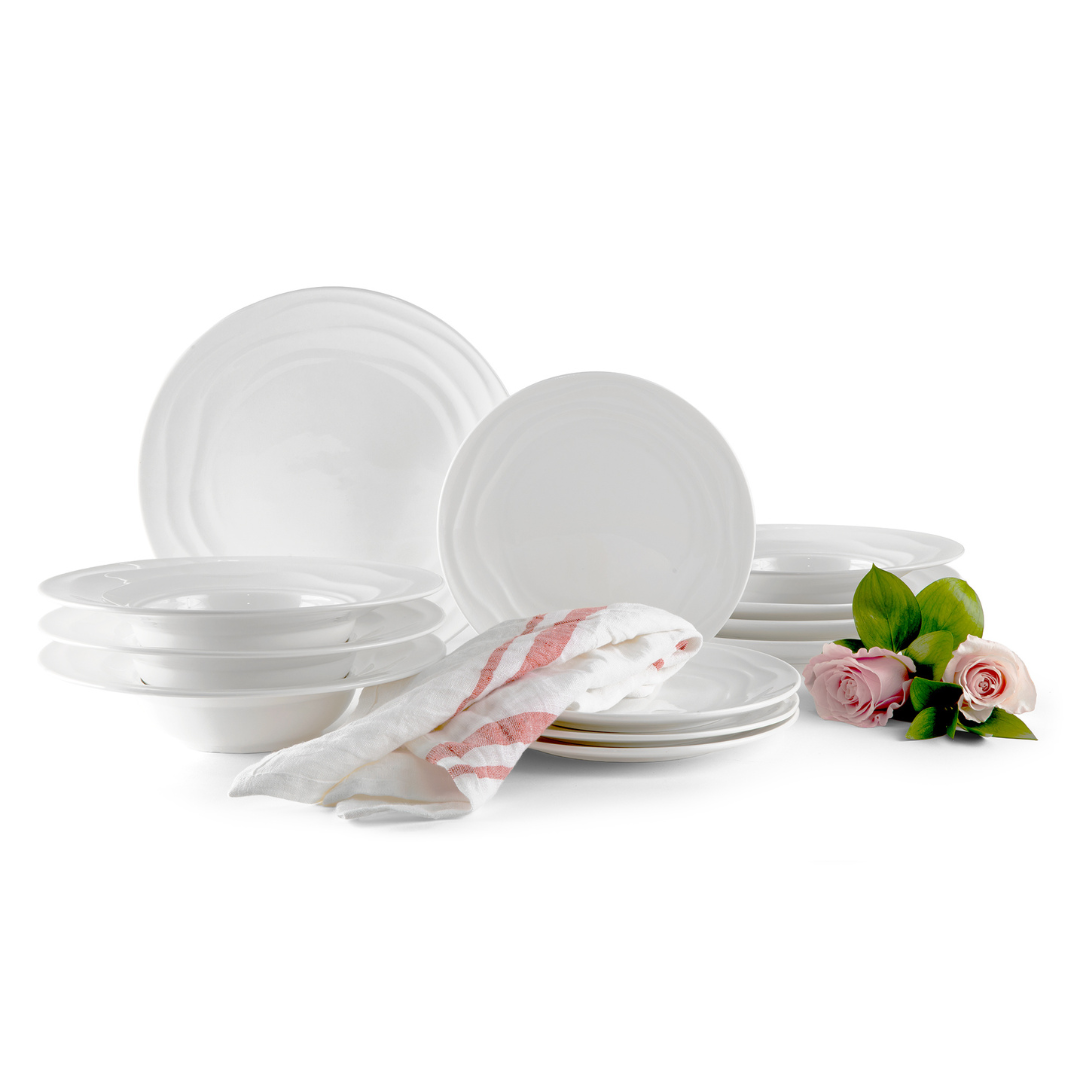 Set of white ceramic dinnerware with a decorative napkin and flowers on a white background