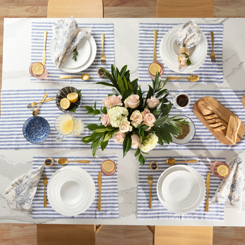 Overhead table set for four with Natural Waves plates, striped linen placemats, flowers and bread