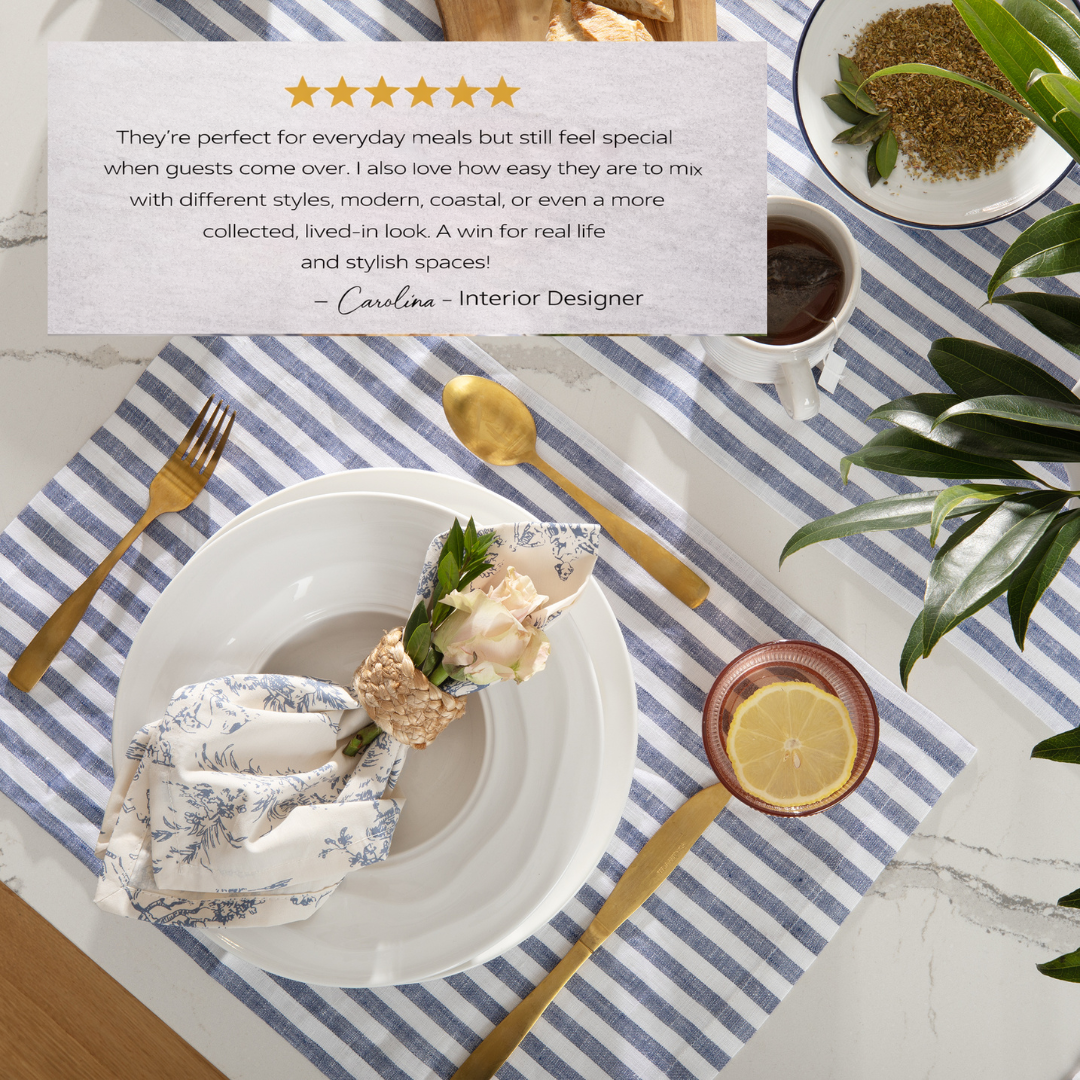 Dining table setting with white plates, gold cutlery, and a striped placemat.